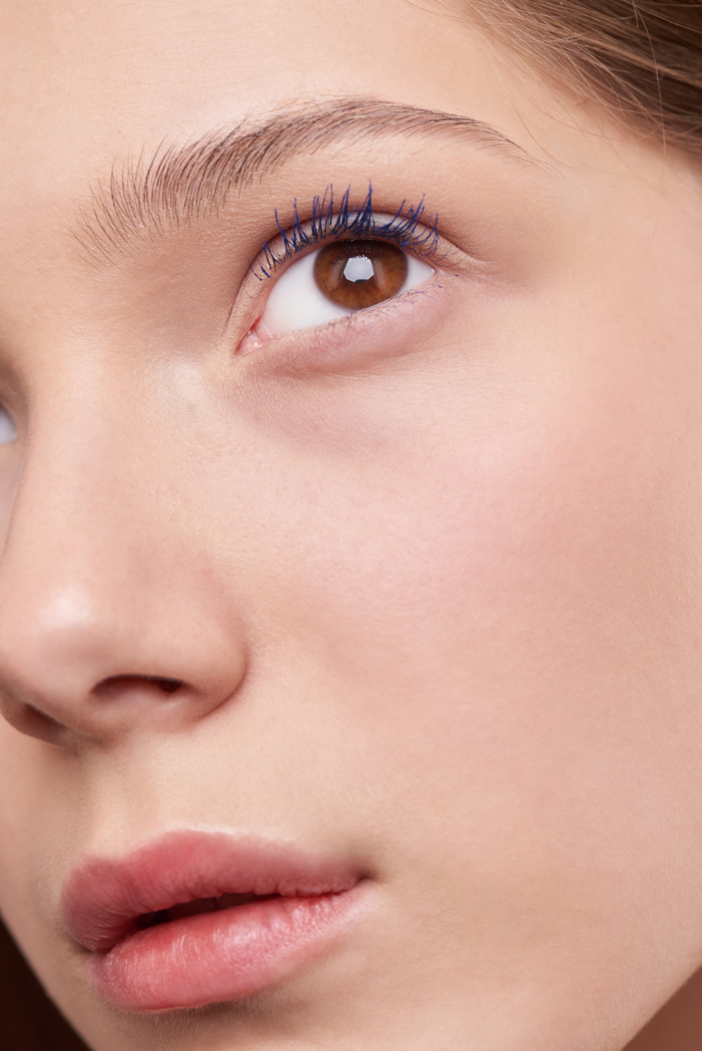 Kvinde med brune øjne, blå mascara og naturlige øjenbryn