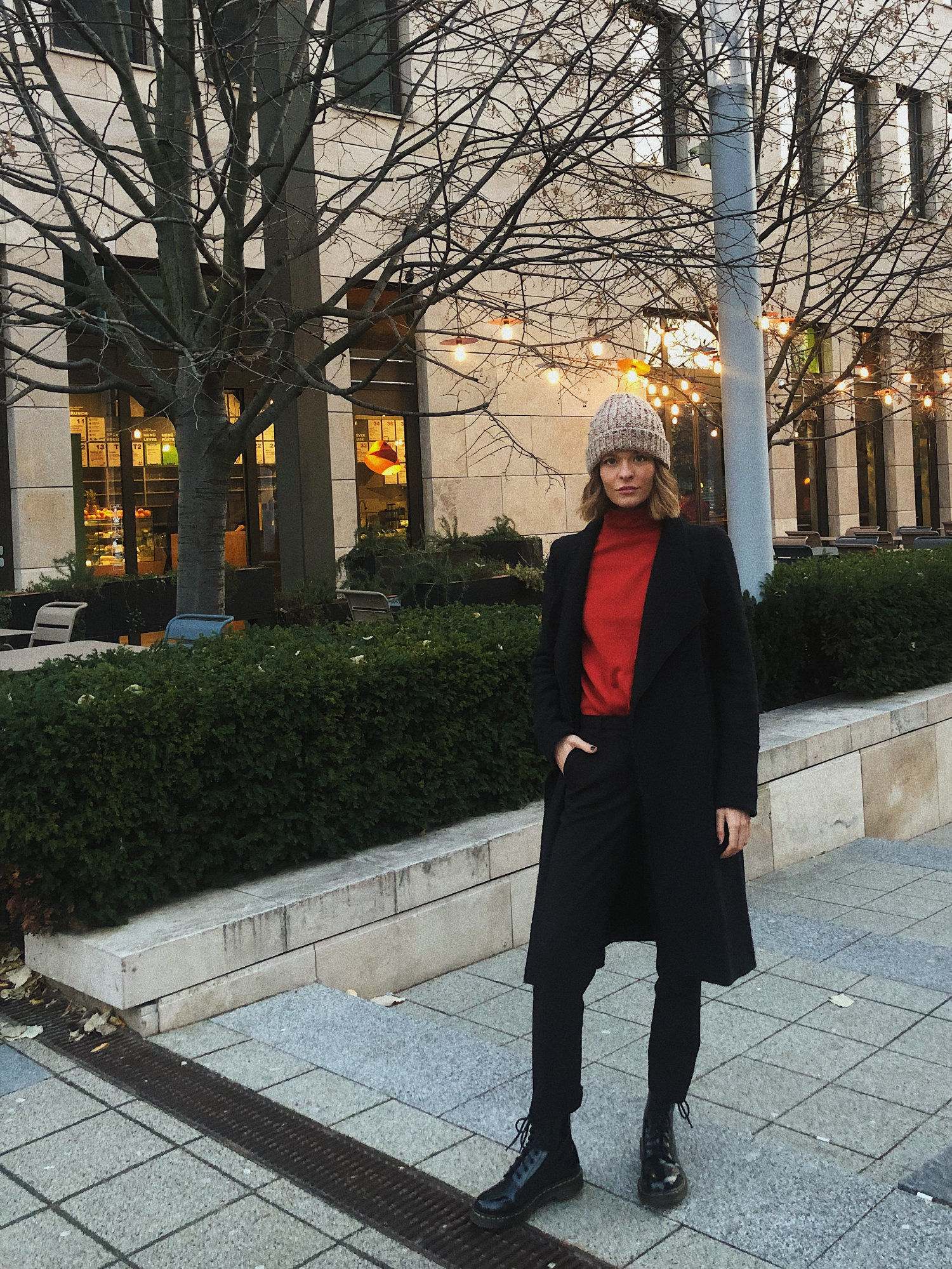 Charlotte Papp iført sort uldfrakke, sorte jeans, røde rullekrave og Dr Martens støvler